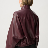 Person wearing a maroon leather jacket on a white background