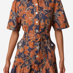 A woman wearing a short-sleeve button-front shirt dress with a ruffled hem and a bold orange floral print on a dark navy background, photographed against a light gray studio backdrop.