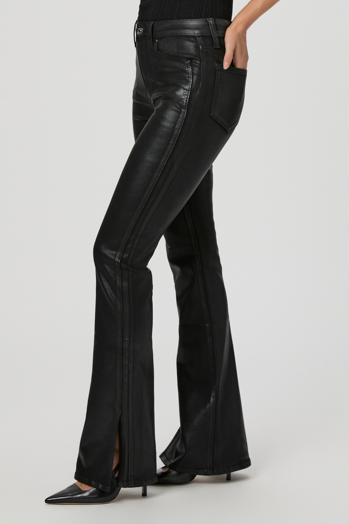 Black leather flared pants worn by a person on a light gray background