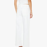 Woman wearing a white sleeveless top and pants on a white background