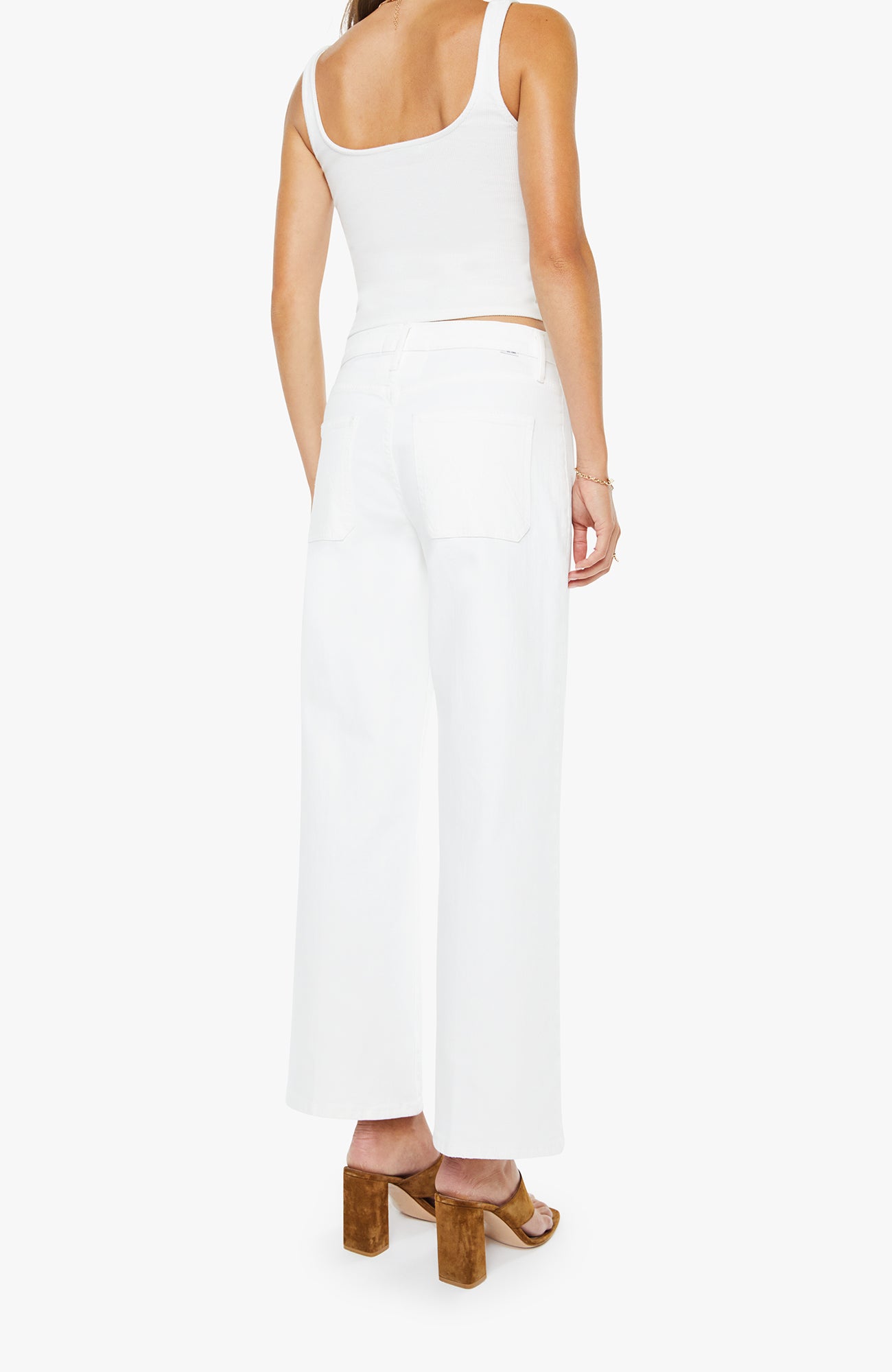 Woman wearing a white sleeveless top and pants on a white background