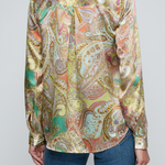 Model wearing printed blouse with jeans on a white background.
