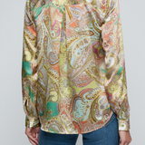 Model wearing printed blouse with jeans on a white background.