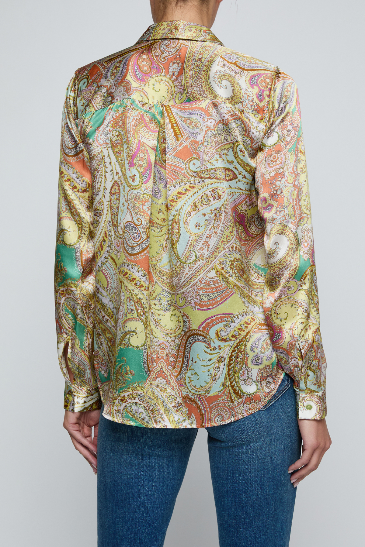 Model wearing printed blouse with jeans on a white background.