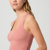 Woman wearing a pink ribbed tank top against a plain background
