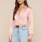 Woman wearing a light pink blouse and light blue jeans with a beige background