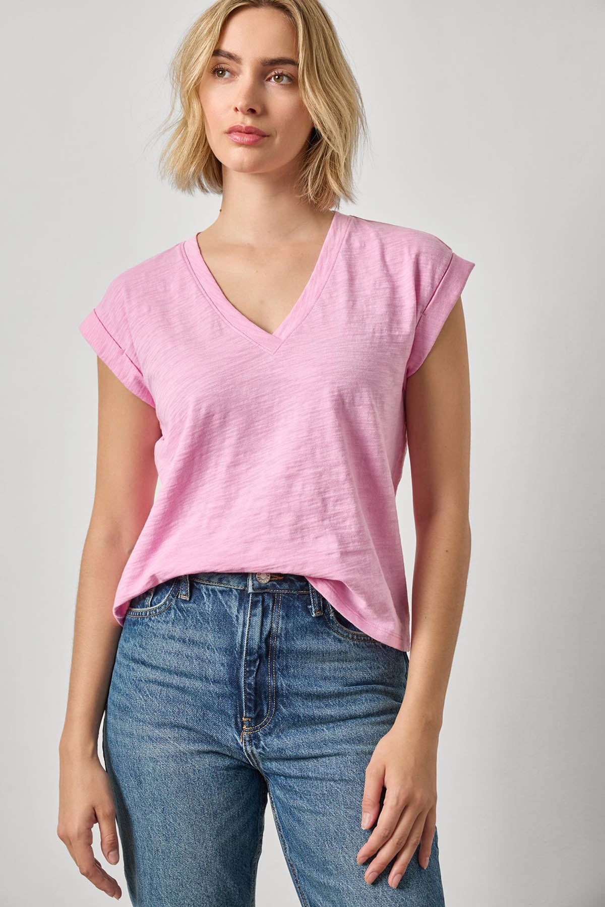 Woman wearing a pink t-shirt and blue jeans on a plain background