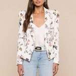 Woman wearing a floral blazer over a white top and blue jeans on a beige background