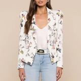 Woman wearing a floral blazer over a white top and blue jeans on a beige background