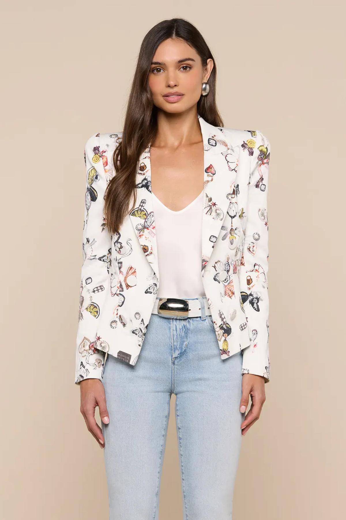 Woman wearing a floral blazer over a white top and blue jeans on a beige background