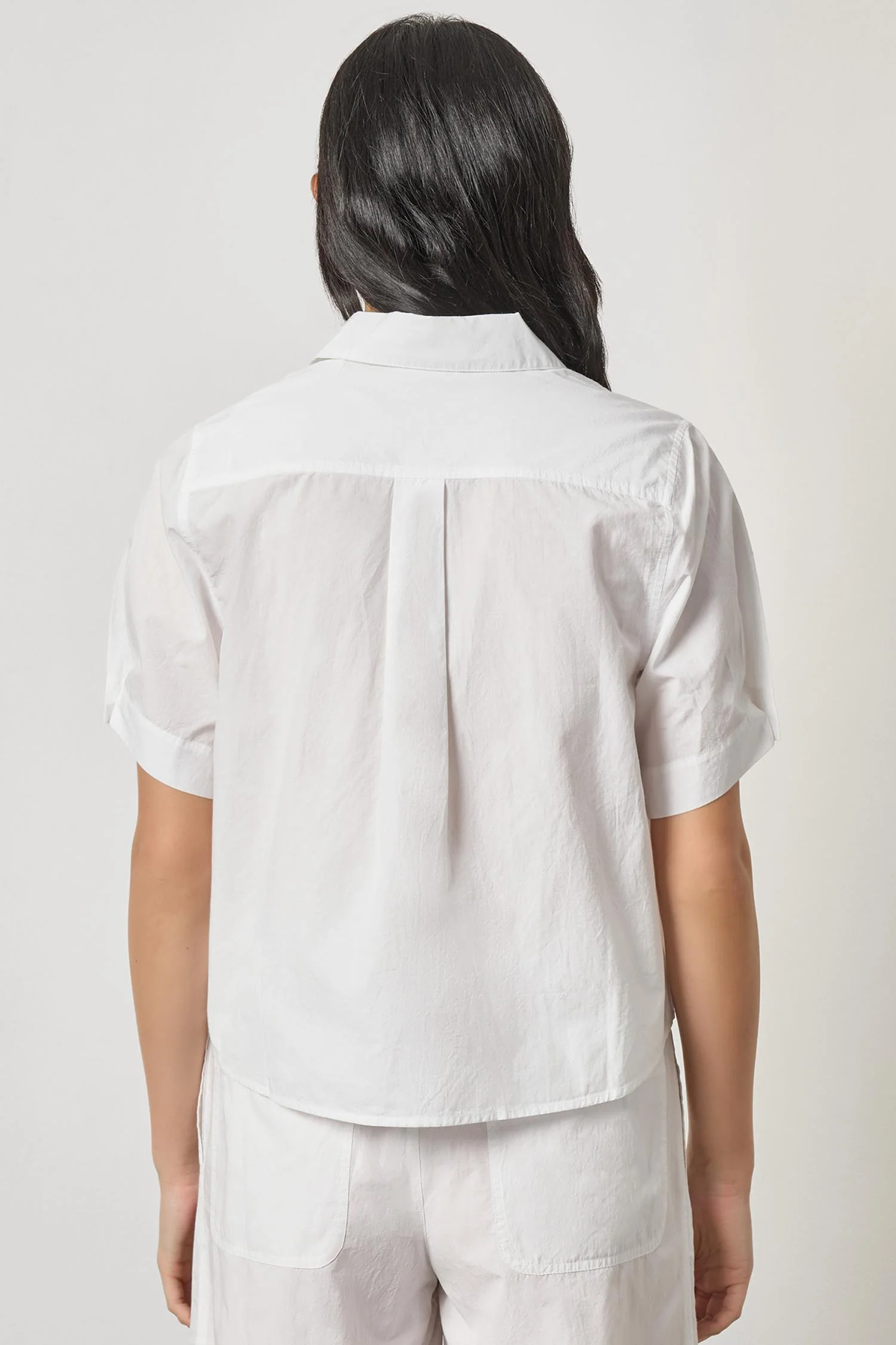 Person wearing a white shirt and pants on a plain background