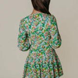 Woman wearing a floral dress with long sleeves on a plain background