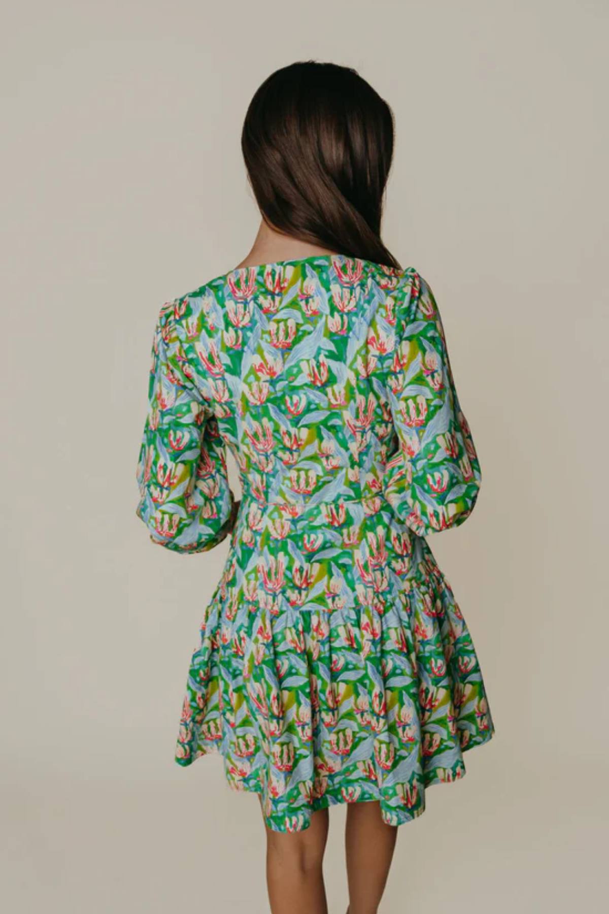 Woman wearing a floral dress with long sleeves on a plain background