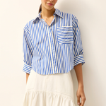 Woman wearing a blue and white striped shirt with a plain background