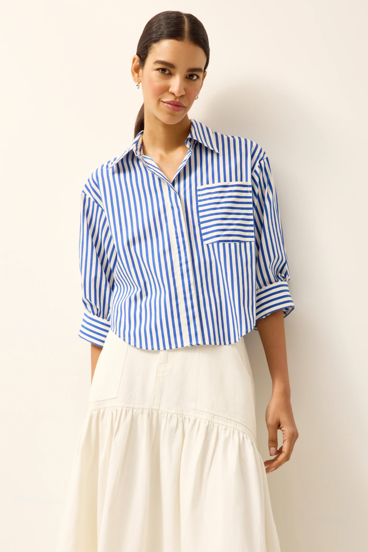 Woman wearing a blue and white striped shirt with a plain background