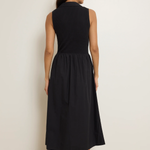 Woman wearing a black sleeveless dress against a plain background