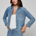 Woman wearing a denim jacket and jeans on a gray background