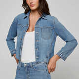 Woman wearing a denim jacket and jeans on a gray background