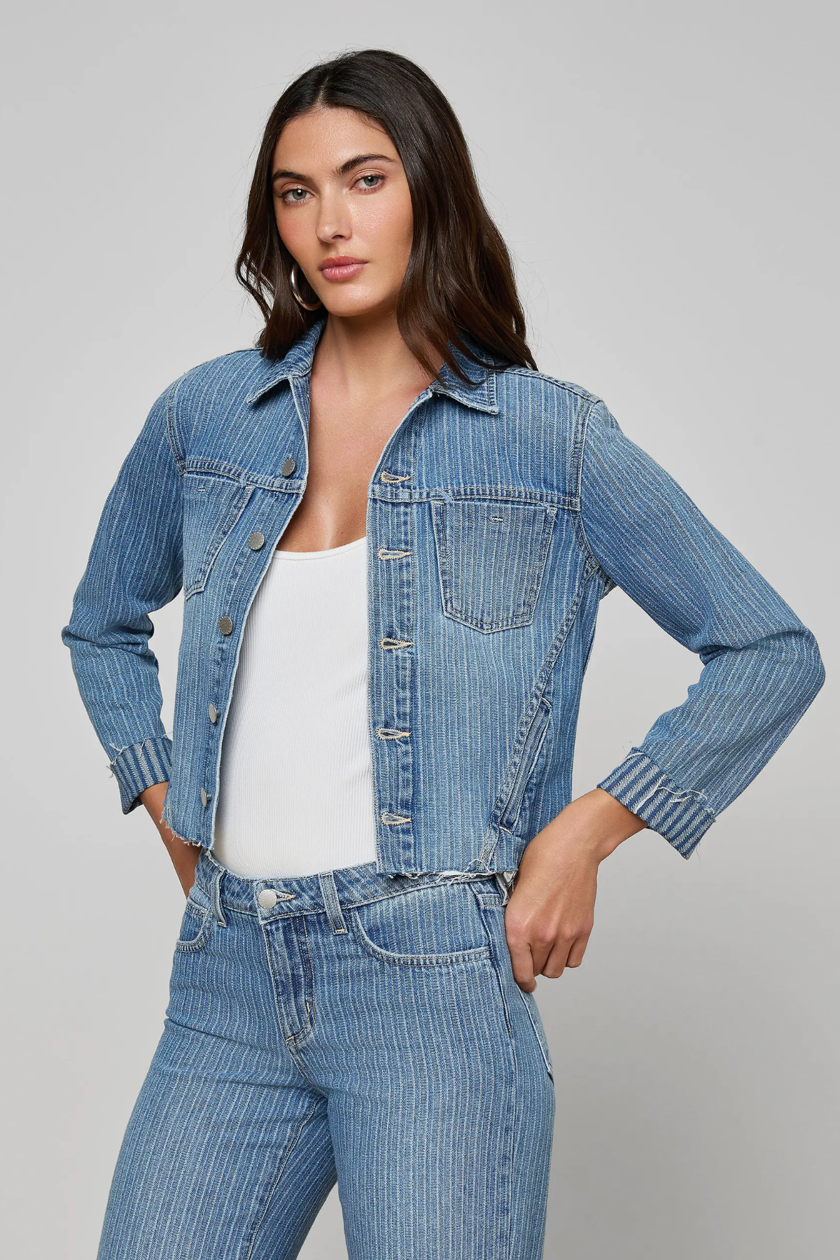 Woman wearing a denim jacket and jeans on a gray background