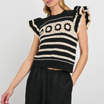 Woman wearing a black and white patterned sleeveless top against a plain background