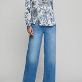 Person wearing a floral blouse and blue jeans on a gray background