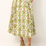 Person wearing a green floral skirt on a white background