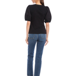 Woman wearing a black top and blue jeans on a white background