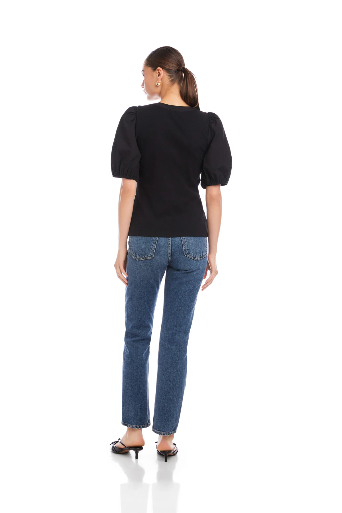 Woman wearing a black top and blue jeans on a white background