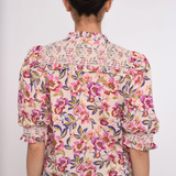 Person wearing a floral blouse with a plain background