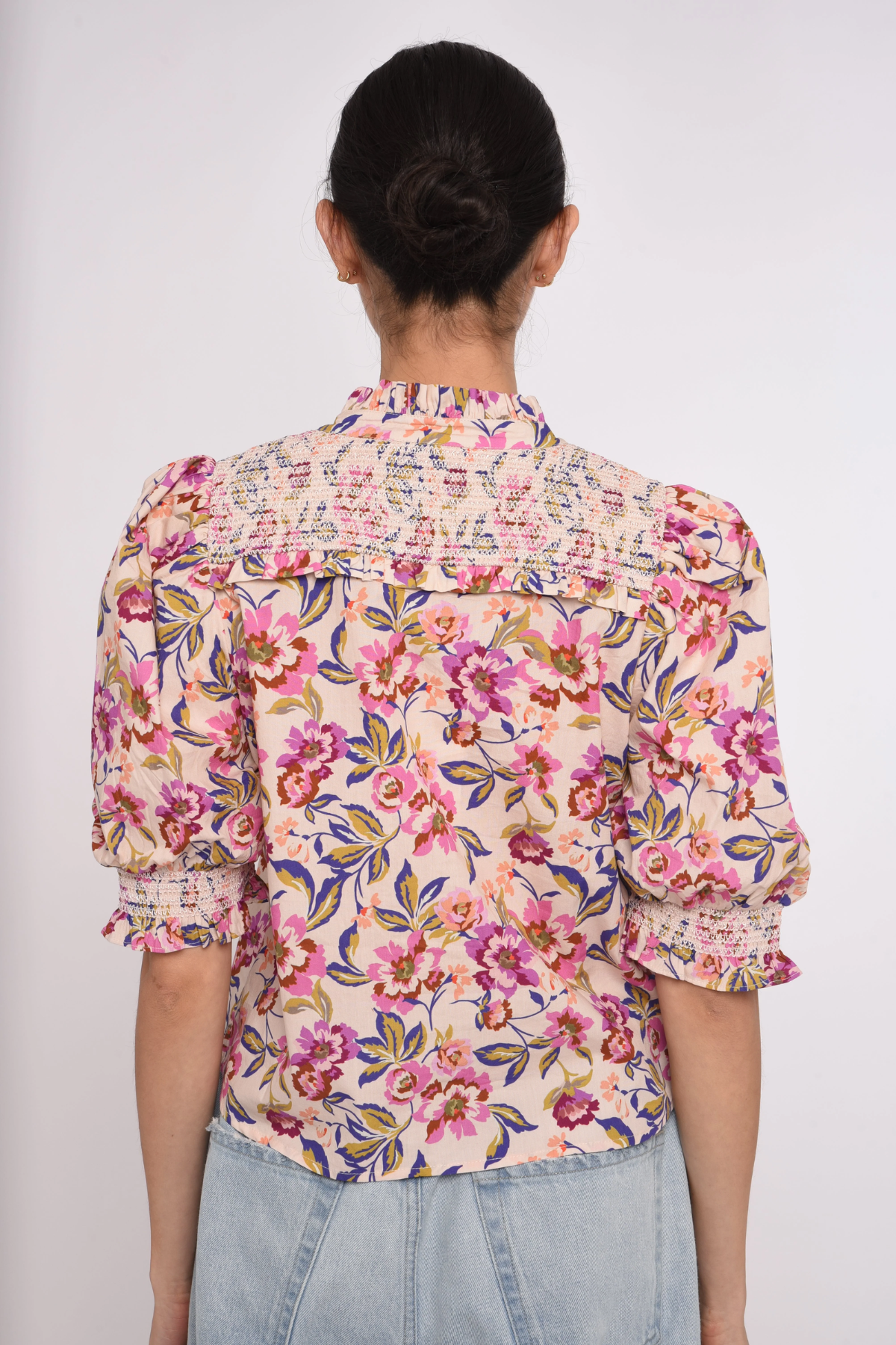 Person wearing a floral blouse with a plain background