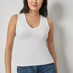 Model wearing a white sleeveless V-neck knit tank with blue denim.