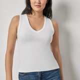 Model wearing a white sleeveless V-neck knit tank with blue denim.