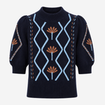 A navy blue knit sweater with puff sleeves, featuring a light blue diamond pattern on the front, brown floral motifs, and decorative chain-like details on the sleeves, shown against a plain light gray background.