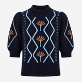 A navy blue knit sweater with puff sleeves, featuring a light blue diamond pattern on the front, brown floral motifs, and decorative chain-like details on the sleeves, shown against a plain light gray background.