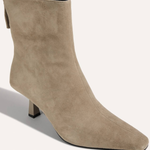 A taupe suede ankle boot with a pointed toe and a low block heel, shown from a three-quarters angle on a light beige background.