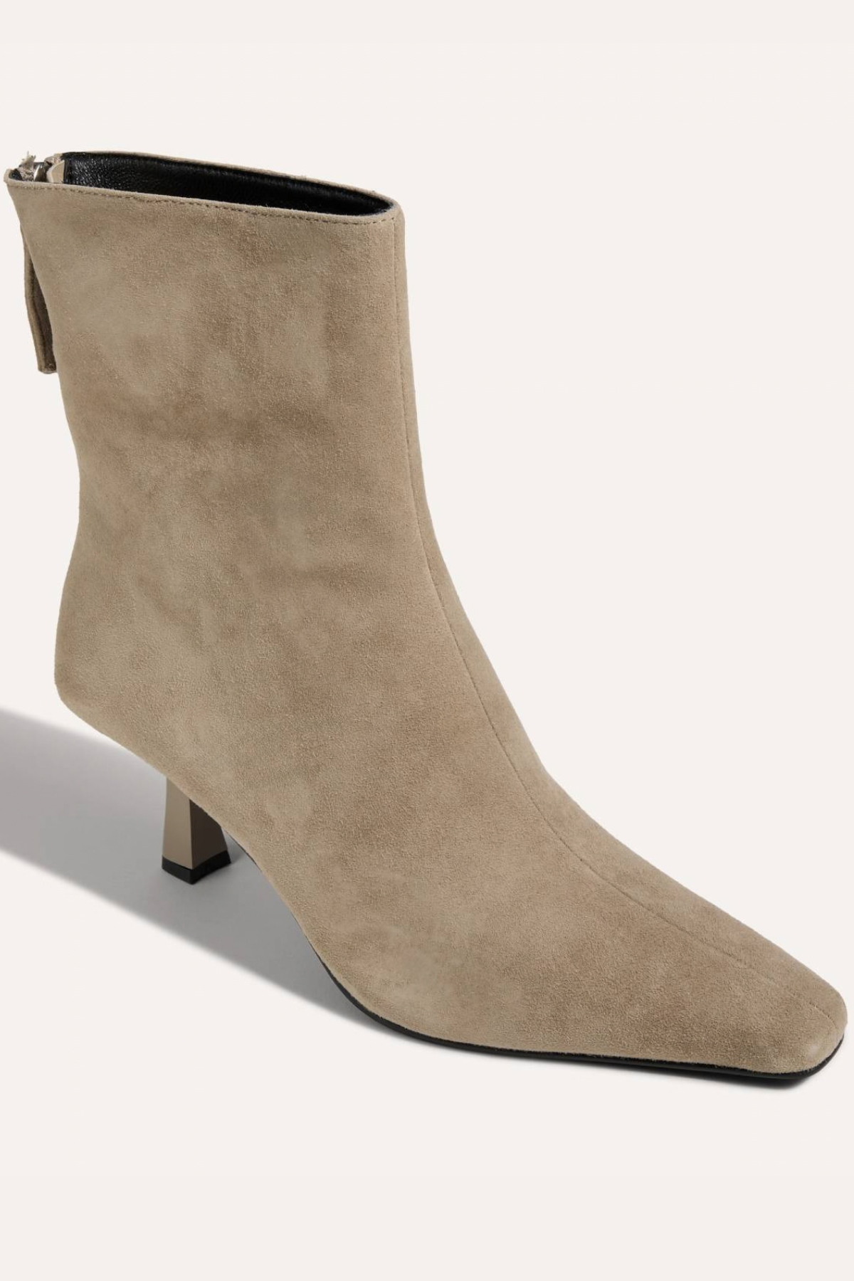 A taupe suede ankle boot with a pointed toe and a low block heel, shown from a three-quarters angle on a light beige background.