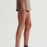 Person wearing beige shorts and brown sandals on a white background