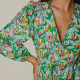 Woman wearing a green floral dress with a neutral background