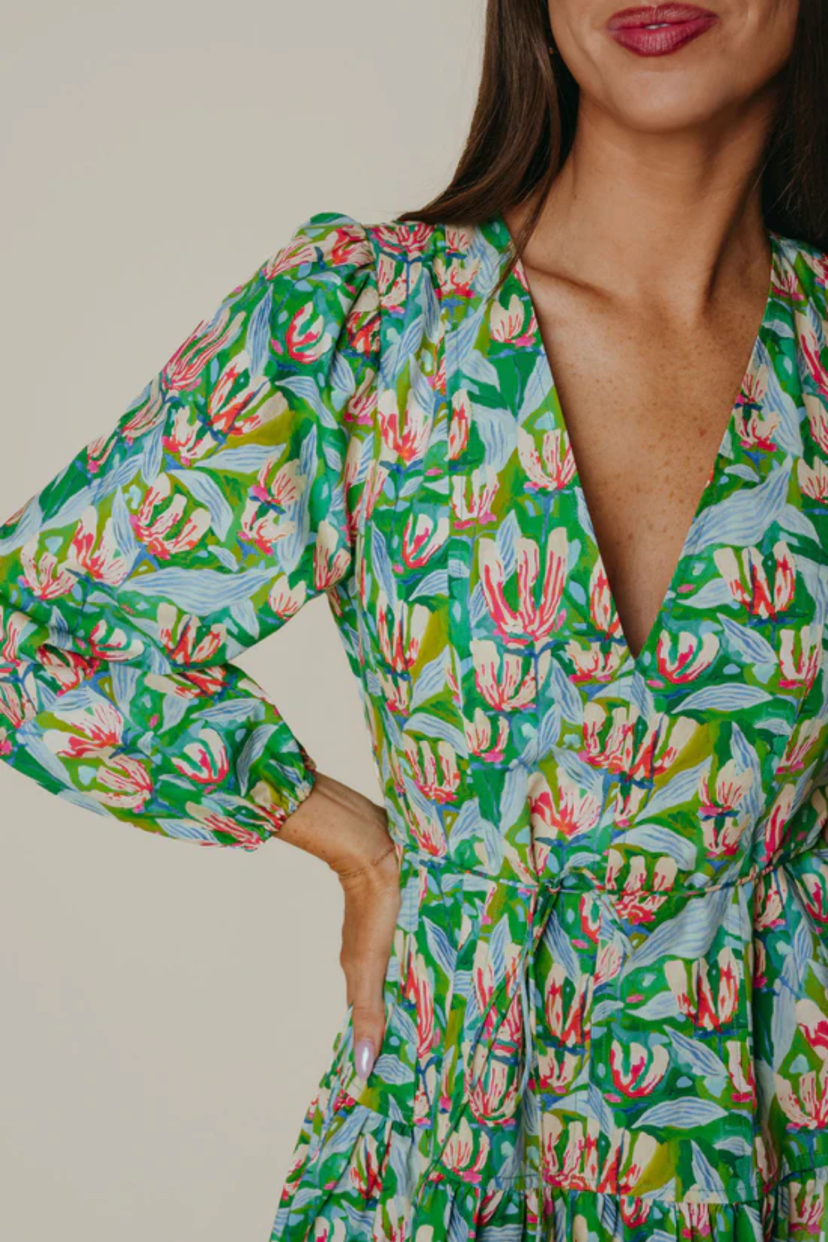 Woman wearing a green floral dress with a neutral background