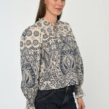 Woman wearing a patterned long sleeve blouse with a gathered neckline in neutral tones