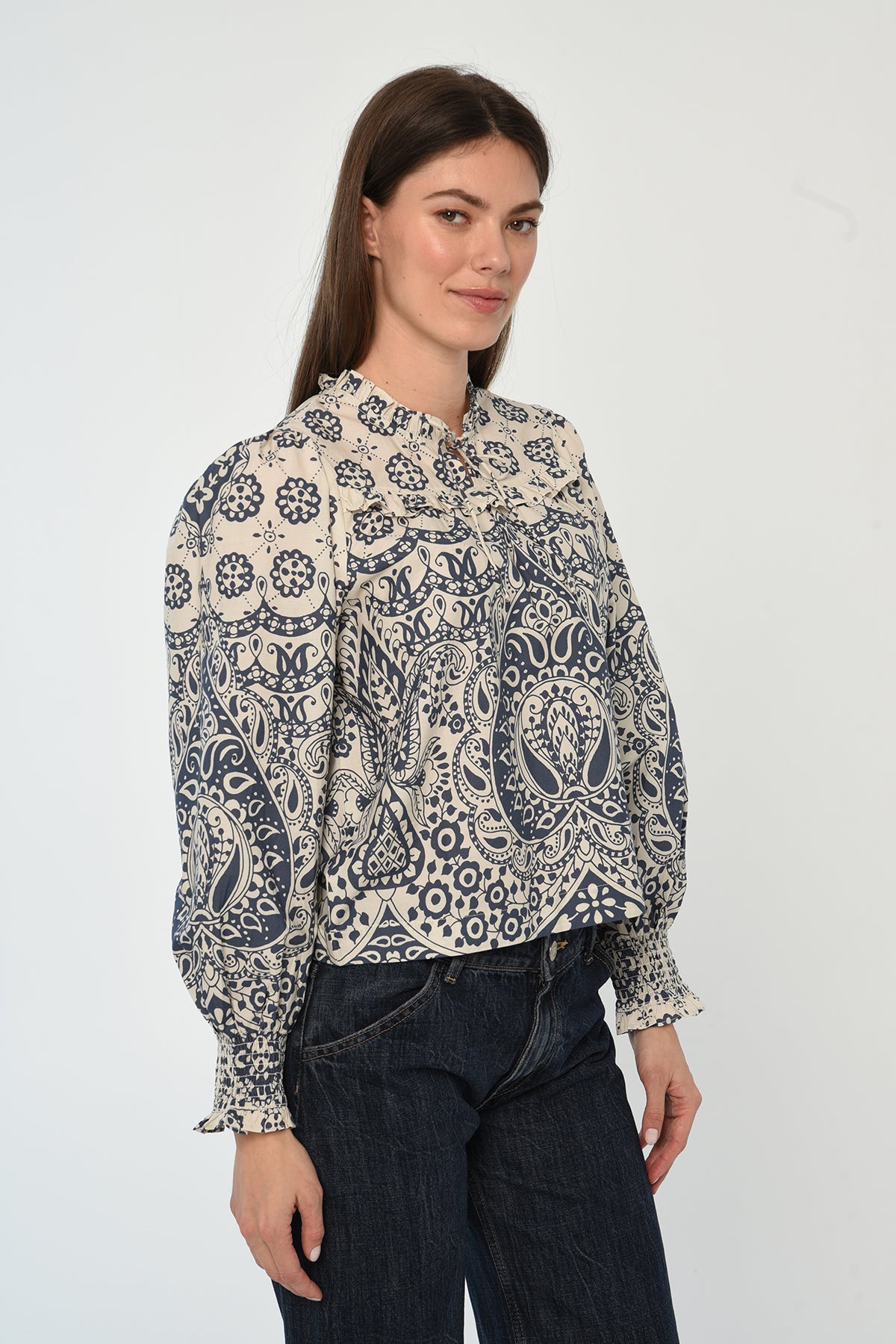 Woman wearing a patterned long sleeve blouse with a gathered neckline in neutral tones