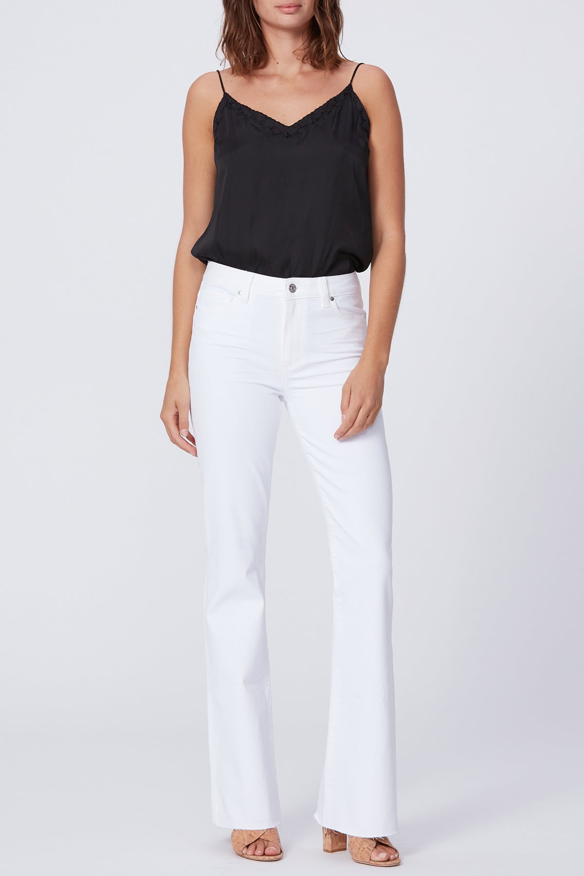 Woman wearing a black top and white pants on a plain background