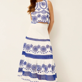 Woman wearing a white dress with blue floral patterns on a plain background