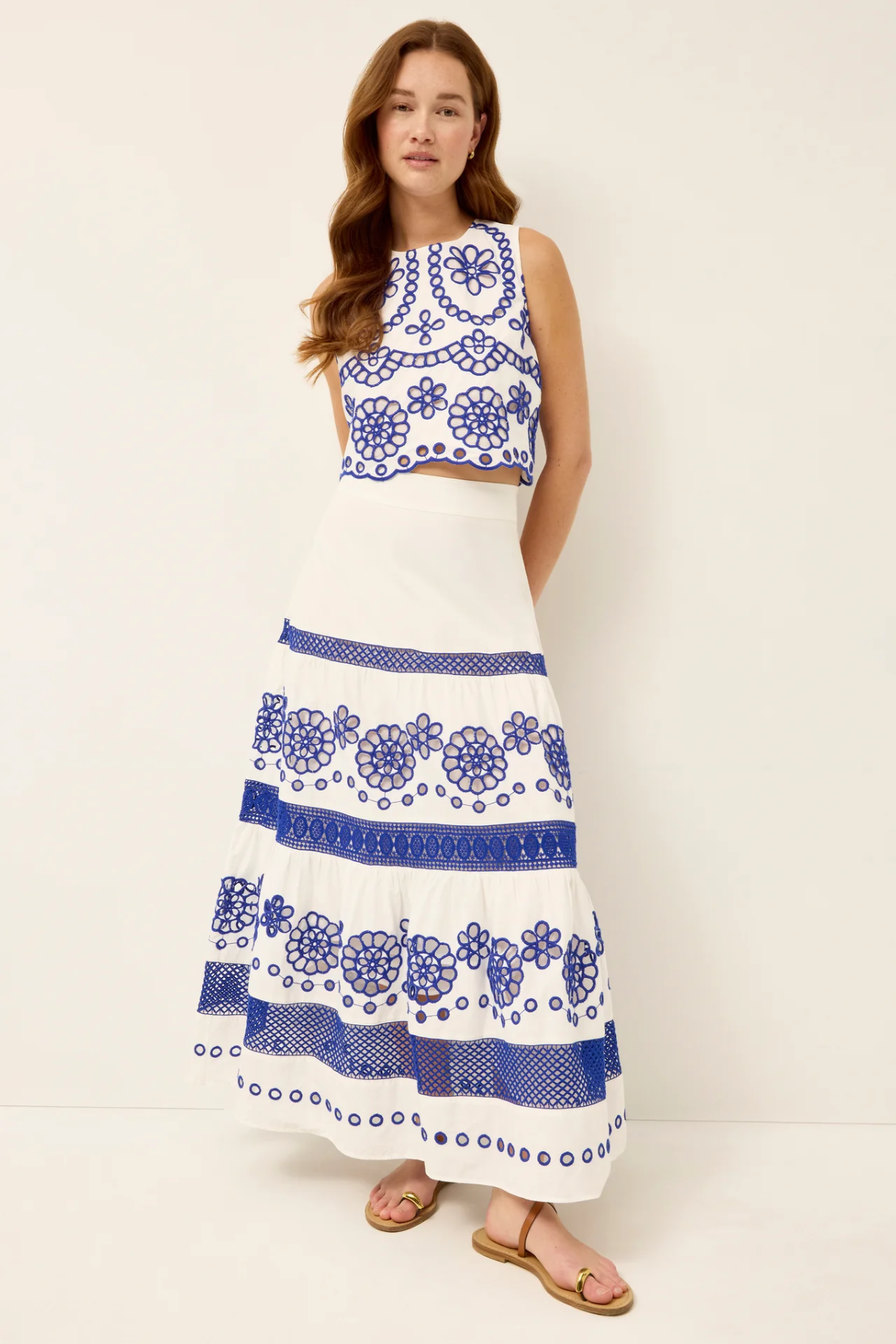Woman wearing a white dress with blue floral patterns on a plain background