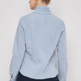 Model wearing a striped long-sleeve blouse with ruffle detailing and a relaxed, polished silhouette.