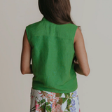 Person wearing a green sleeveless top with floral pants on a plain background
