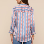 Woman wearing a blue and red patterned shirt with rolled-up sleeves on a beige background