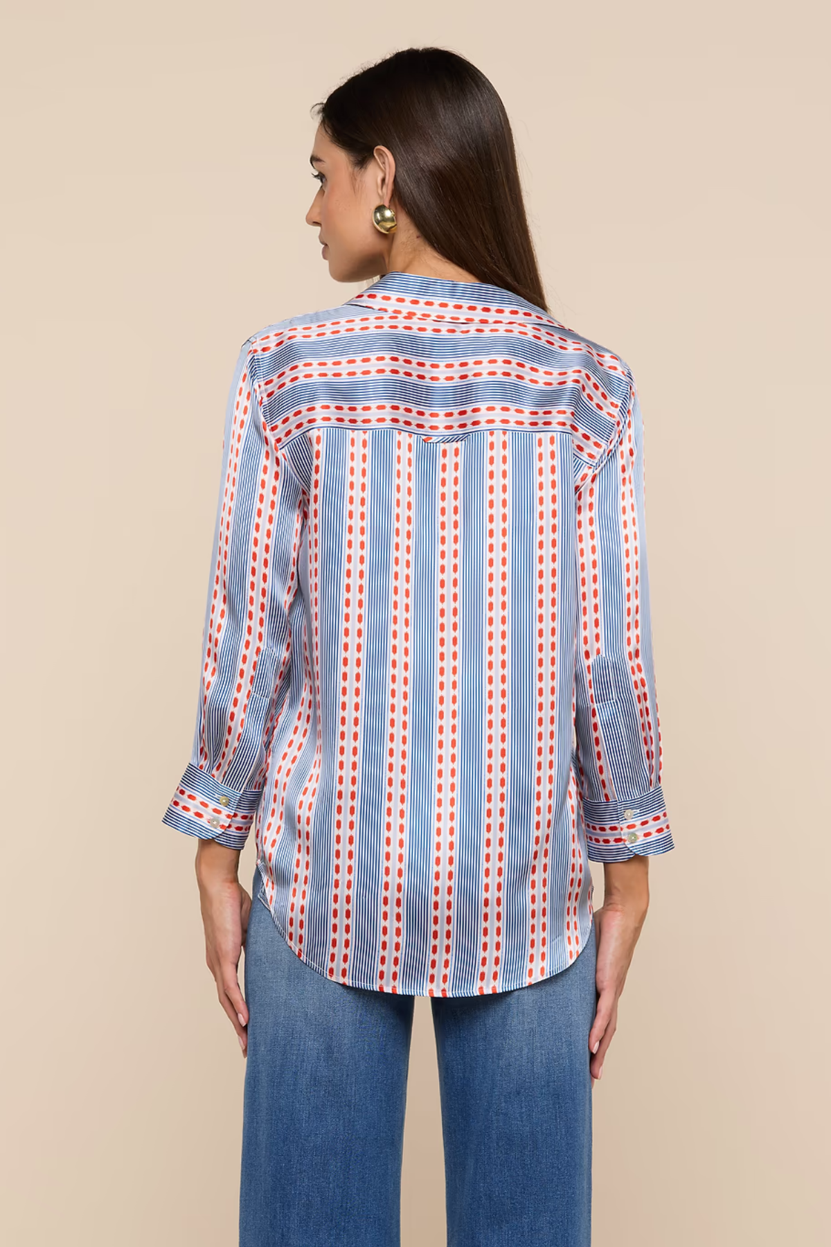 Woman wearing a blue and red patterned shirt with rolled-up sleeves on a beige background