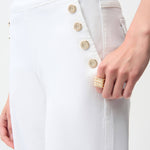 Close-up of a white coat with gold buttons and a hand wearing a ring on a white background