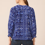 Woman wearing a blue patterned blouse with a beige background